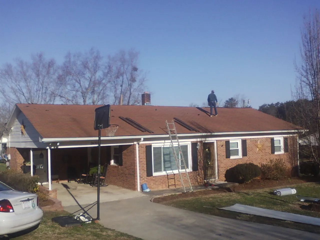 Roofer stripping a shingle roof on a brick ranch before metal panels in Custer City