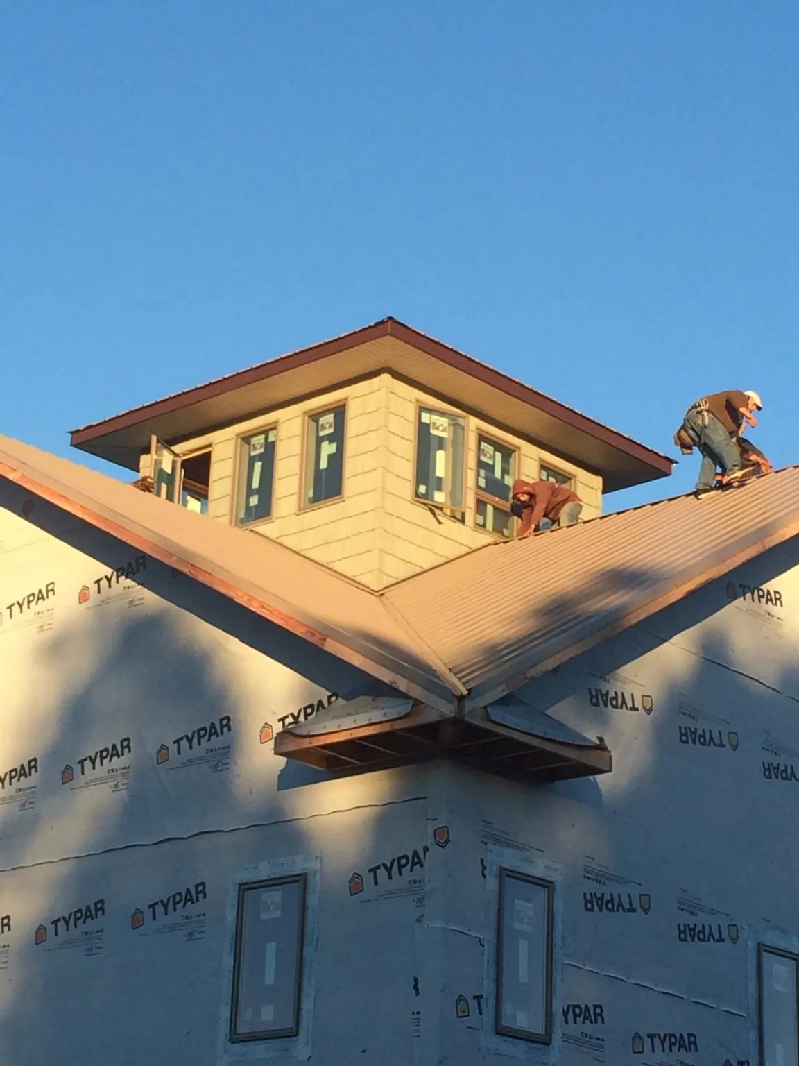 Roofers working around a rooftop cupola on a new metal roof at sunset — Roof Waterproofing in Custer City by Roofing Brothers